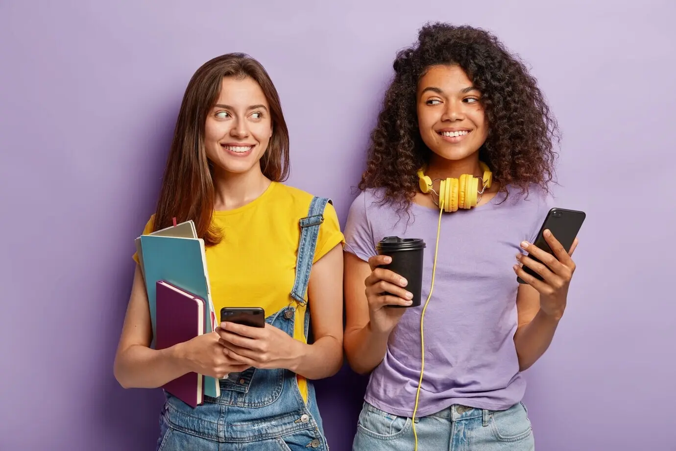 Innenaufnahme von zwei sympathisch aussehenden, fröhlichen Studienkollegen mit gemischtem ethnischem Hintergrund, die nach den Vorlesungen eine Kaffeepause machen.